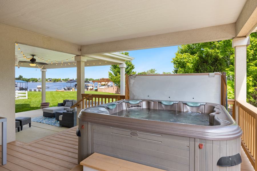 Spa posé sur la terrasse en bois d'un porche avec vue sur un lac